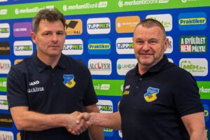Schindler Szabolcs és Tamási Zsolt kézfogása a Gyirmót FC háttérfala előtt.