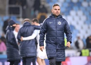 Horváth Dávid kabátban a pálya szélén, háttérben MTK-játékosokkal.